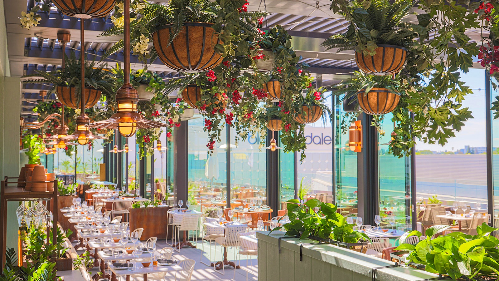 The patio-like dining area of Terra, at Eataly Silicon Valley, with floor-to-ceiling windows and hanging baskets of flowers